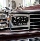 Chrome-edged black badge reading 2500 Injection, angled studio shot on stand