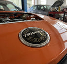 Laurel wreath badge fitted to the bonnet of an orange Triumph