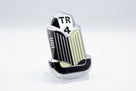 Chrome TR4 bonnet badge with cream and black enamel, studio shot on white