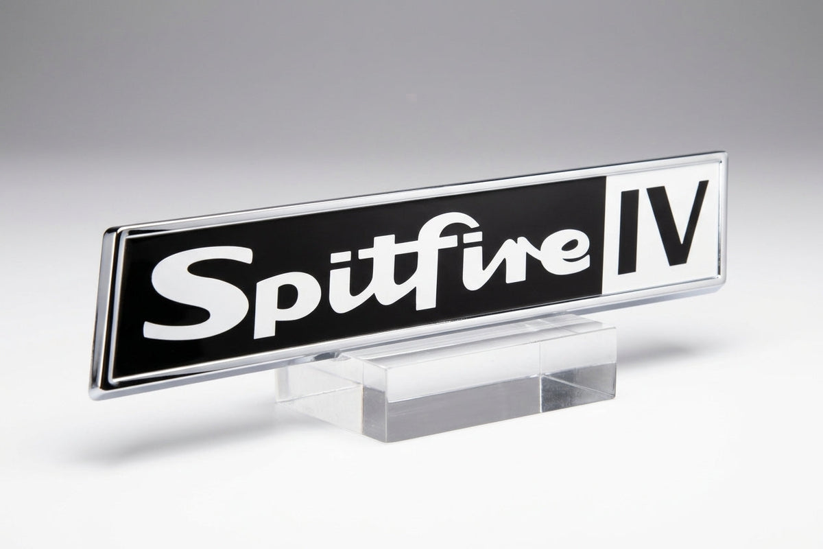 Black enamel Spitfire badge with chrome surround, white script lettering and block IV, on a clear stand