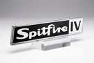 Black enamel Spitfire badge with chrome surround, white script lettering and block IV, on a clear stand