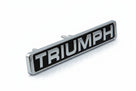 Chrome and black TRIUMPH bonnet badge angled on white background, studio shot