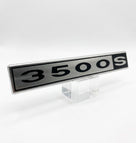 Silver and black 3500S badge displayed on a clear stand, studio shot