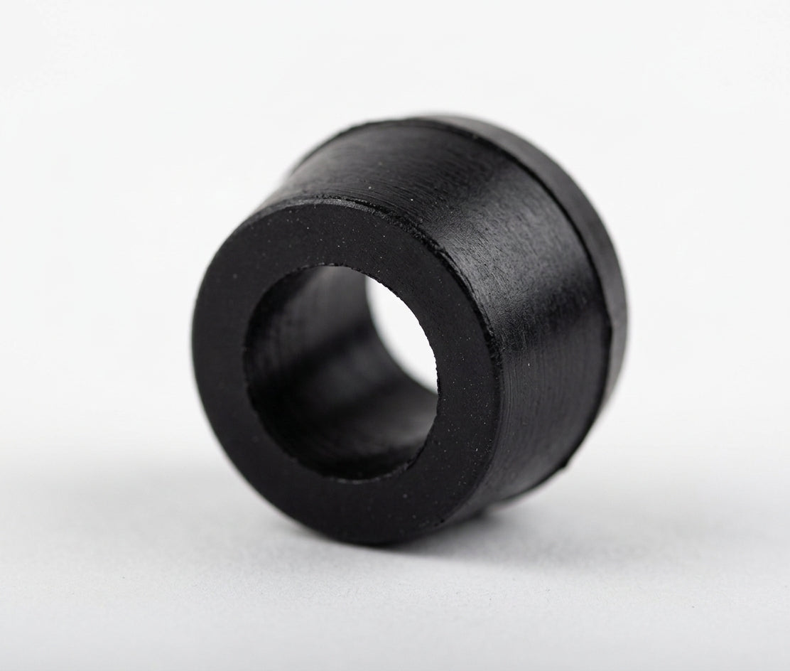 Black cylindrical polyurethane bush with central bore, angled studio shot