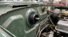 Black steering column bush fitted through the firewall of a green Triumph Stag