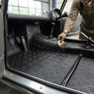Chequer plate matting fitted in a classic car's footwell, being trimmed