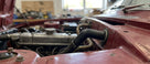 Black elbow connector hose fitted in the engine bay of a red Triumph Stag