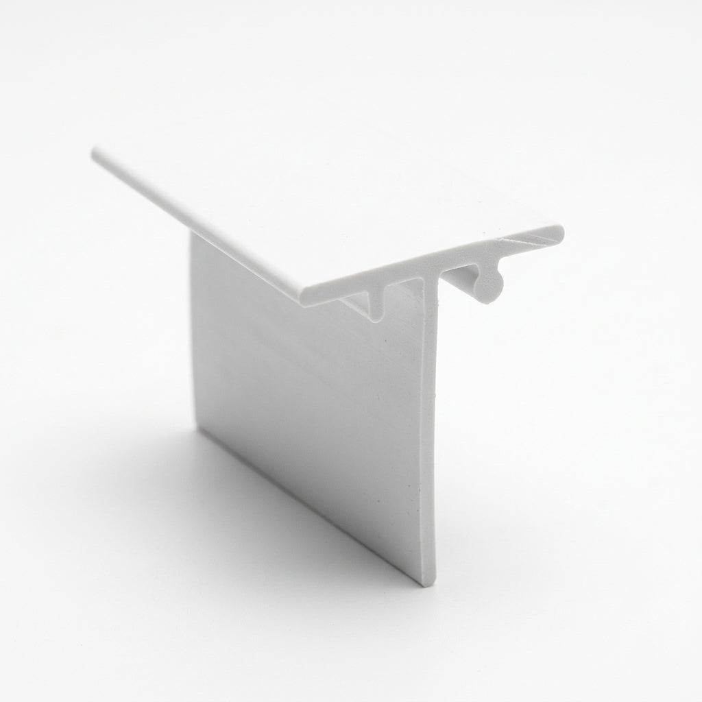 White PVC T-shaped edge trim standing upright, glossy finish, viewed at an angle