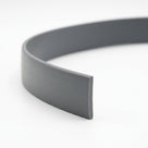 Grey PVC filler coil curled into a loop, showing the flat profile end on white background
