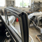 Top seal fitted to a bare metal window frame of a car under restoration in a workshop