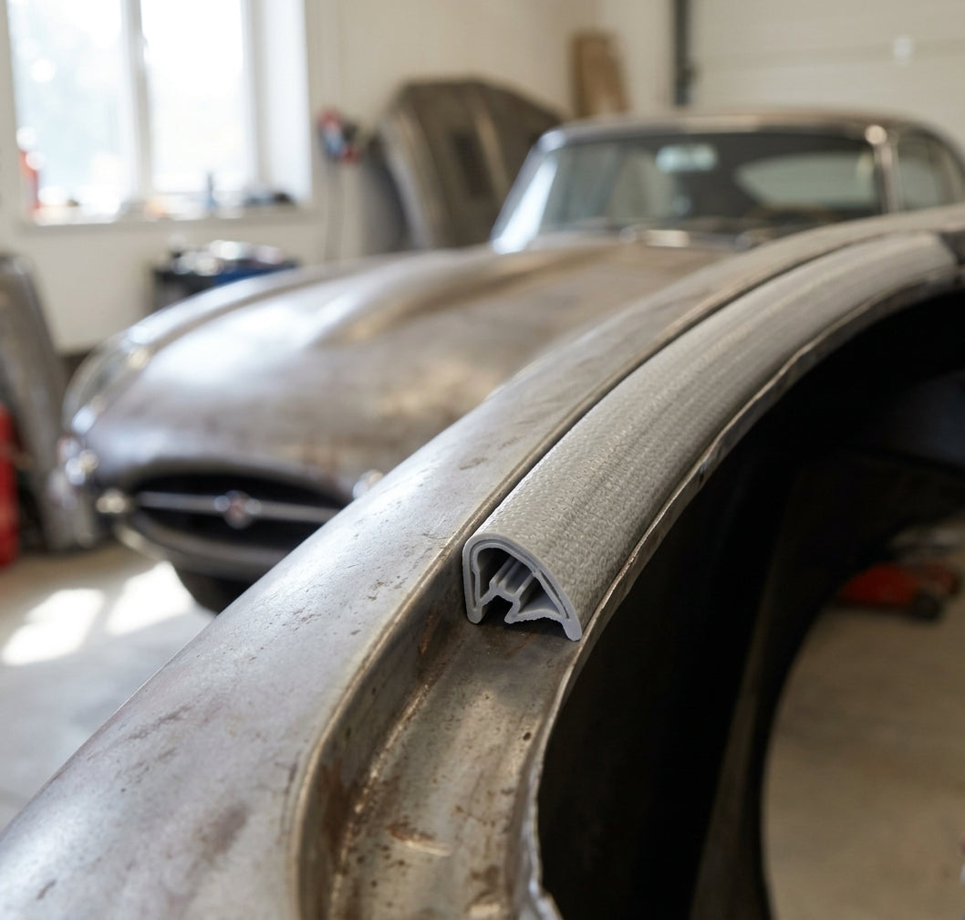 Grey PVC edging strip fitted to an unpainted metal wing edge on a classic sports car