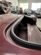 Black EPDM U-channel seal fitted around a rear window aperture on a maroon classic car