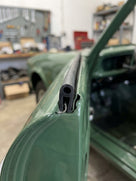 Door seal fitted along the edge of a green Aston Martin's door, in-situ close-up.