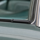 Double ended piping fitted along a green classic car's window trim edge