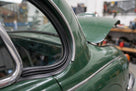 Windscreen seal fitted to the rear quarter window of a green classic Jaguar with bonnet raised