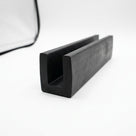 Black EPDM U-channel profile coiled, close-up of square-ended groove on white background