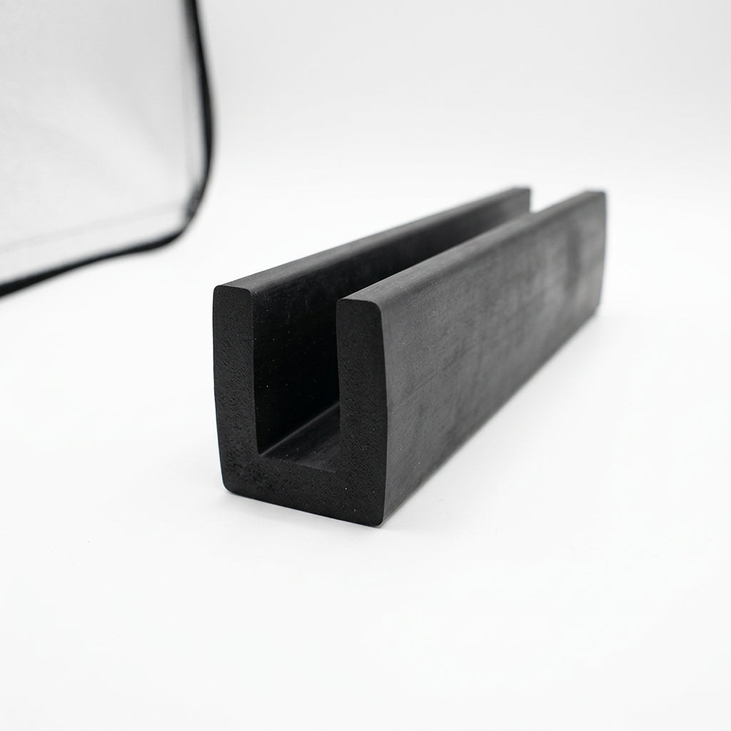 Black EPDM U-channel profile coiled, close-up of square-ended groove on white background