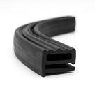Coiled length of black rubber seal showing its ribbed top edge and rectangular hollow channel.