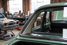 Black windscreen surround fitted to a green Escort's rear side window, workshop