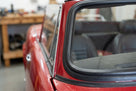 Black windscreen rubber seal fitted around the rear screen of a red classic car