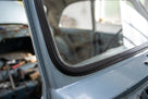 Black windscreen surround fitted to a pale blue Anglia's rear window frame