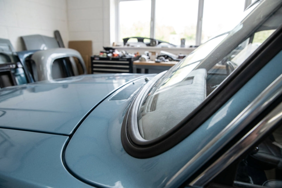 Black windscreen surround fitted to a pale blue Cortina's curved screen corner