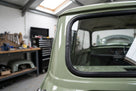Black rubber seal fitted around the rear side window of a green Mini Mk1