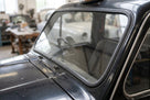 Seal fitted around the windscreen aperture of a dark classic taxi cab in a workshop, viewed along the bonnet