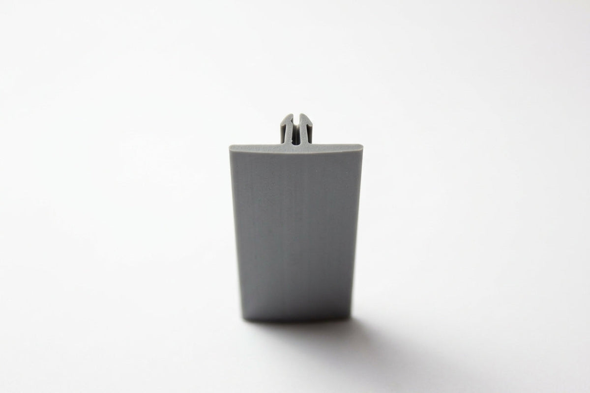 Grey PVC Herzim strip shown end-on, revealing its tapered trapezoid cross-section