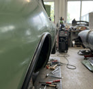 Black trim strip fitted to a wheel arch edge on a green classic car
