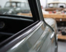Black trim strip fitted along a window frame on a grey-green classic car