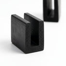 Black neoprene U-channel profile pieces, plain white background shot of square-ended sections