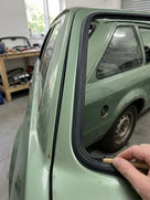 Rear window seal being fitted to a green Escort estate with a trim tool