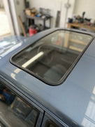 Black sunroof seal fitted around a blue Escort's opening sunroof glass