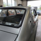Black windscreen seal fitted around a silver Capri's rear side window, workshop
