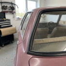 Black windscreen seal fitted to a mauve Cortina's rear screen corner, workshop