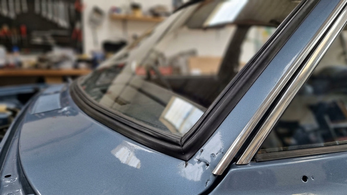 Black windscreen seal fitted to a light blue Cortina's screen corner with chrome trim