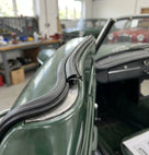 Black edge trim fitted along the windscreen frame of a green convertible