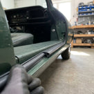 Gloved hand fitting black edge trim to a car door sill, green bodywork visible