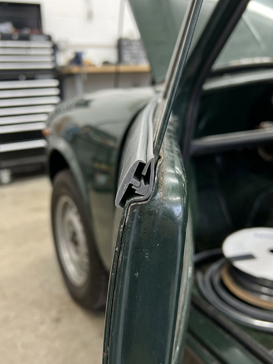 Grey edge trim clipped onto a wing edge of a dark green classic car