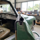 Self-grip seal fitted to a green classic car's door pillar in a workshop