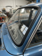 Black windscreen surround fitted to a blue Cortina's rear window with chrome trim