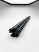Length of black windscreen seal with twin locking channels, close-up on white background