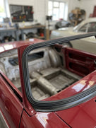 Black windscreen seal fitted around the screen aperture of a red MGB roadster shell