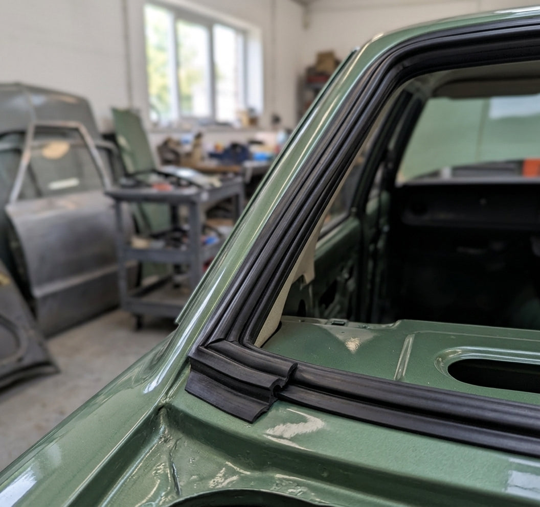 Black windscreen seal fitted to a green Cortina's screen corner, workshop