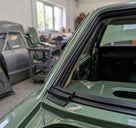 Black windscreen seal fitted to a green Cortina's screen corner, workshop