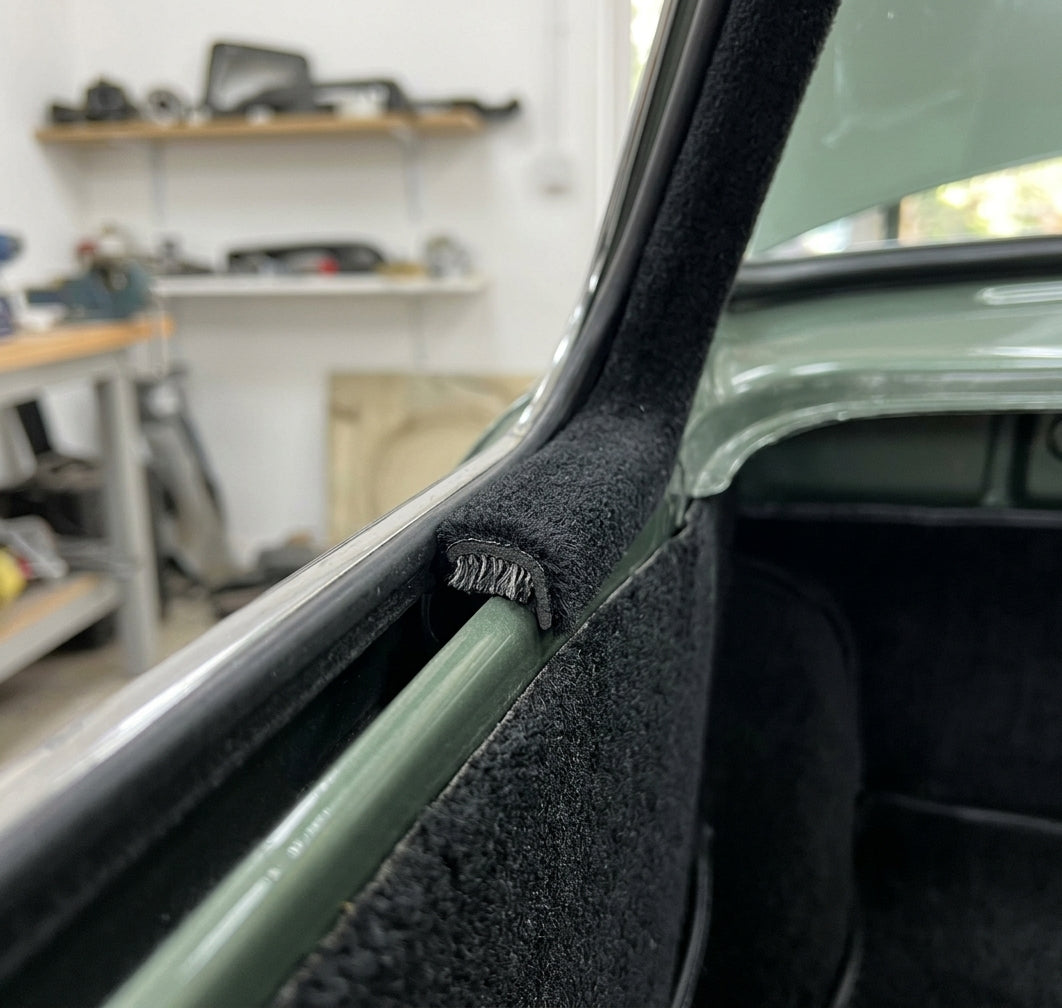 Black carpet-covered edge trim fitted to a door pillar on a green classic car