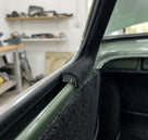 Black carpet-covered edge trim fitted to a door pillar on a green classic car