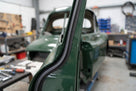 Black sponge strip fitted along a door aperture of a green classic car in a workshop