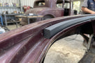 Sponge strip fitted along the roof edge of a maroon vintage car in a workshop